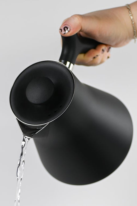 Fellow Corvo black electric kettle being held and pouring water on white background