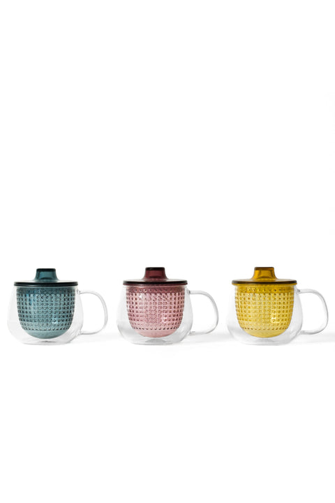Three Unimug double-walled glass tea infuser mugs with colored textured inserts and lids in teal, pink, and yellow on white background